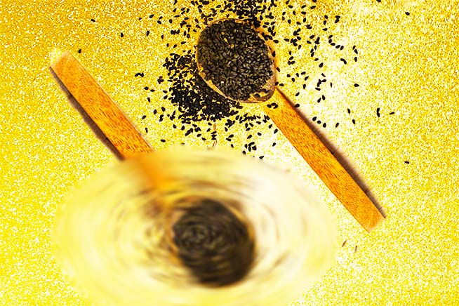 two wodden spoons with black seeds in them - black seed oil for your face article - prestige provisions